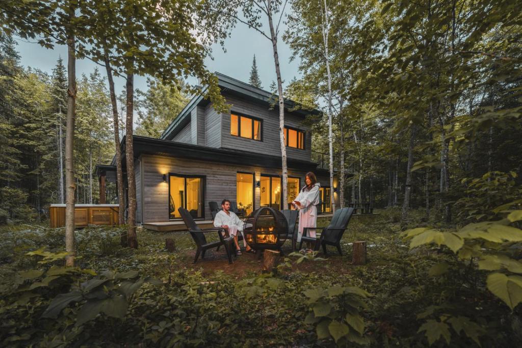 a couple standing in front of a tiny house at Chalet la coulée douce, Expérience thermale privée in Saint Come