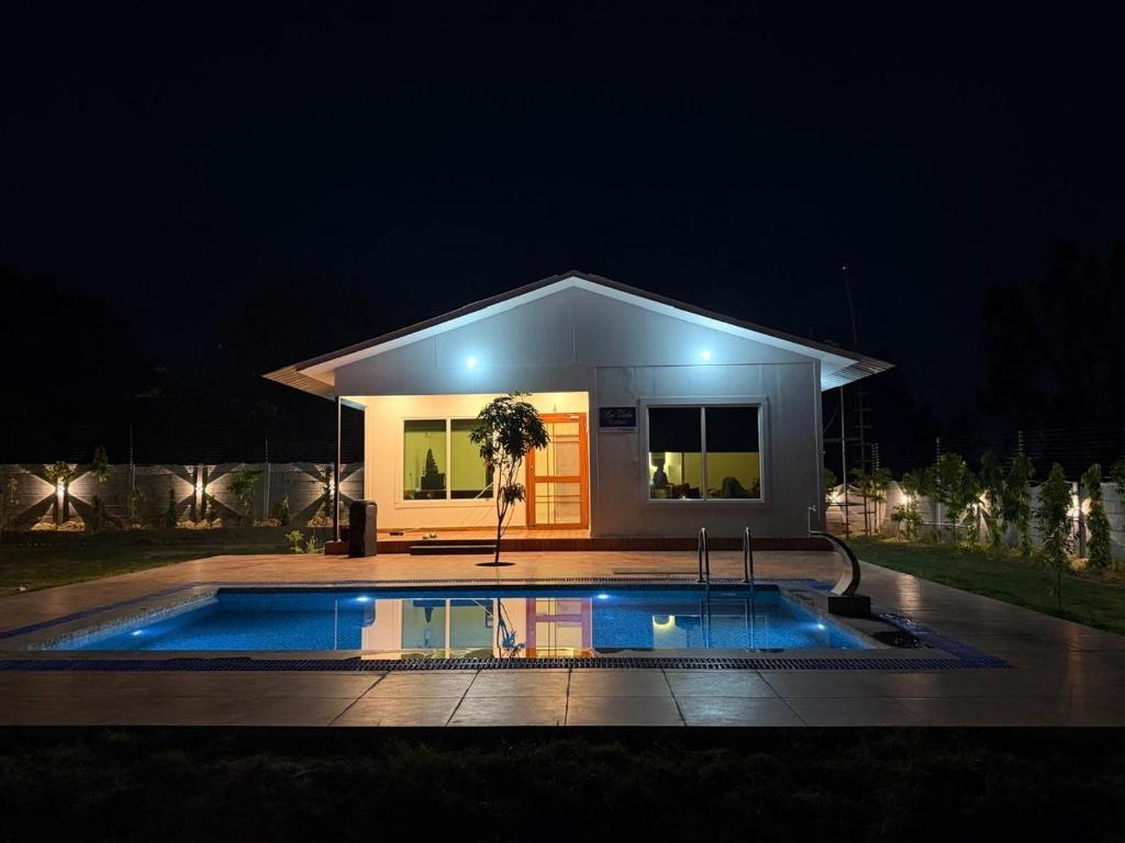 a small house with a swimming pool at night at La Vida Estate Farm in Garhmuktesar