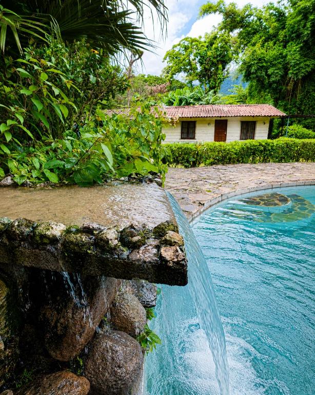 a swimming pool with a waterfall in front of a house at Hotel Rincón Vallero in Valle de Anton
