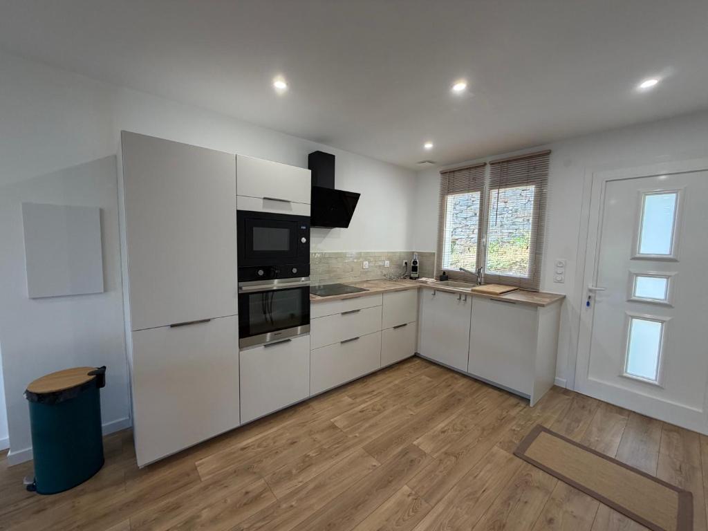 an empty kitchen with white cabinets and appliances at Charmant appartement sur les hauteurs d'Erbalunga in Brando