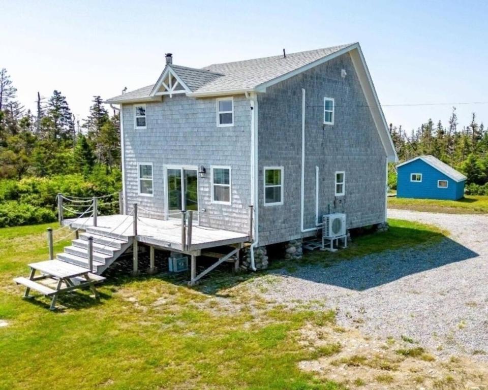 a large gray house with a porch and a dock at Ocean Pines seaside cottage in Shelburne