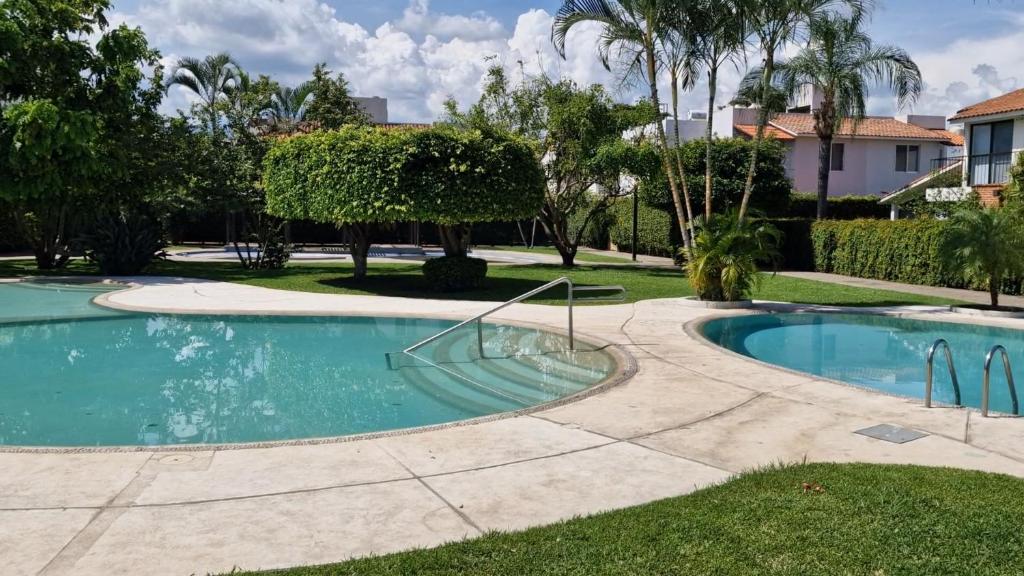 a swimming pool in a yard with trees and a house at Casa Viveros cerca de jardines 3 recamaras albercas y 2 estacionamientos in Jiutepec