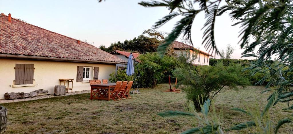 a house with a table and chairs in the yard at Maison au bord de dune et océan in Labenne