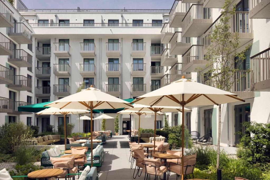 a hotel patio with tables and chairs and umbrellas at Schwan Locke in Munich