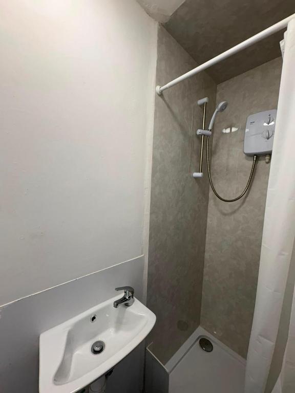a white bathroom with a sink and a shower at Goody Suites in Newcastle upon Tyne