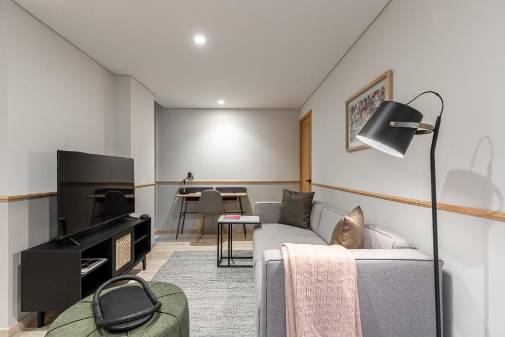 A living area combines a gray sofa, television and compact dining-work table.