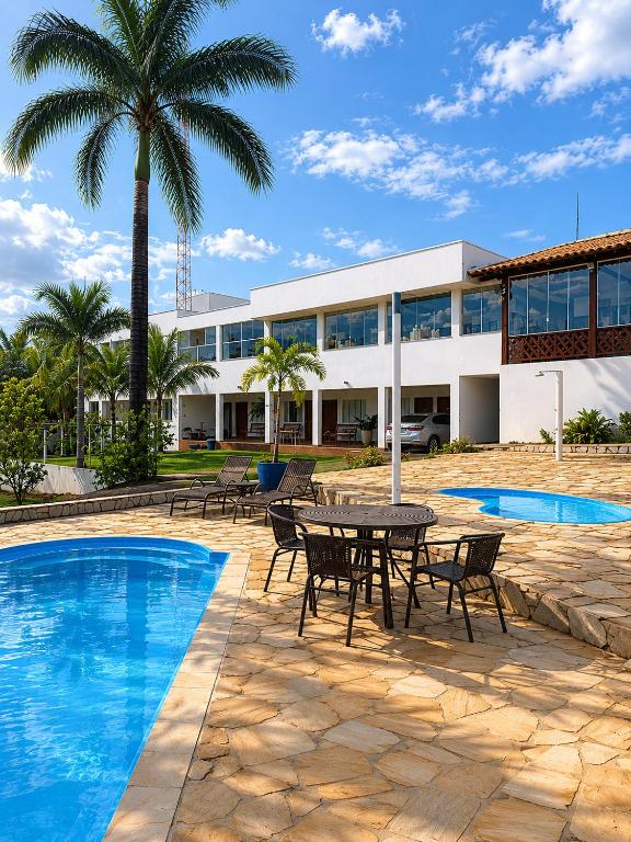 a resort with a table and chairs next to a pool at Pousada Escarpas in Capitólio