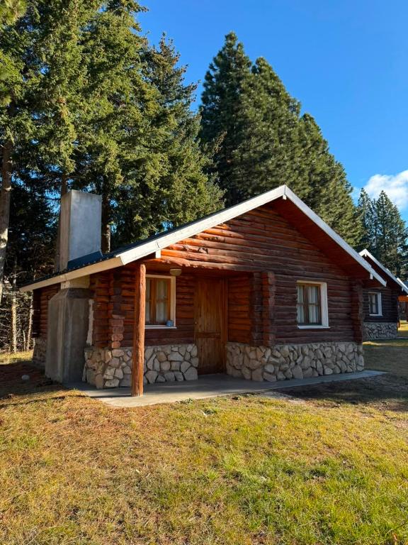 a log cabin with a stone wall at Complejo Villa Azul in Esquel