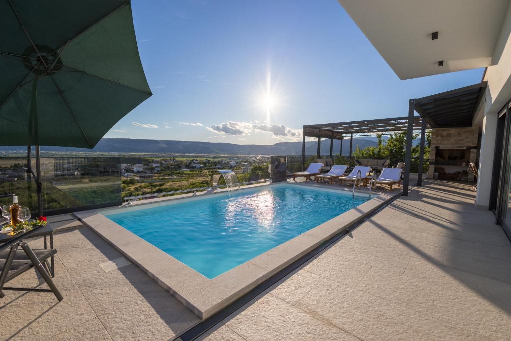 a swimming pool with an umbrella on top of a house at Villa Sunset Mostar in Mostar