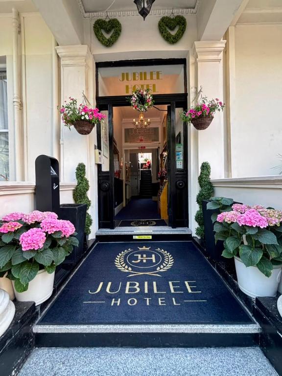 a hotel entrance with a welcome mat and flowers at Jubilee Hotel Victoria in London