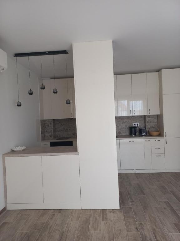 a white kitchen with white cabinets and a wooden floor at Рока Ресиденс 1 in Ravda
