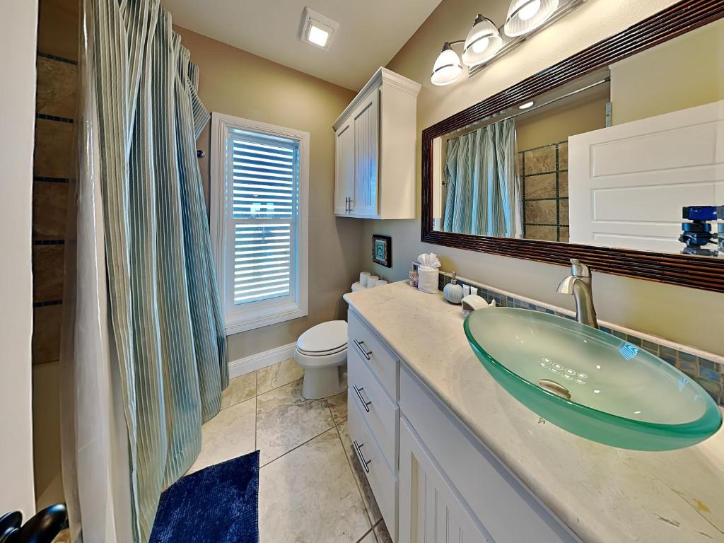 a bathroom with a sink and a toilet and a mirror at Baja Breeze in Port Aransas