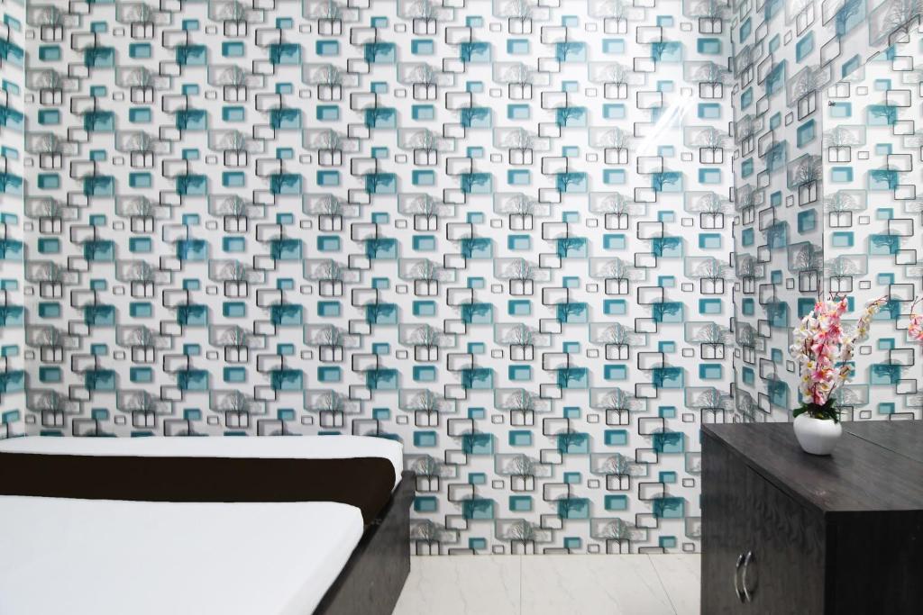 a bathroom with a bath tub and a wall with a pattern at Hotel O New Taj in Baharampur