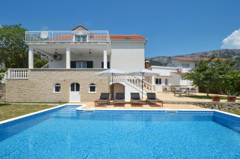 a villa with a swimming pool and a house at Holiday Home Nevera in Kaštela