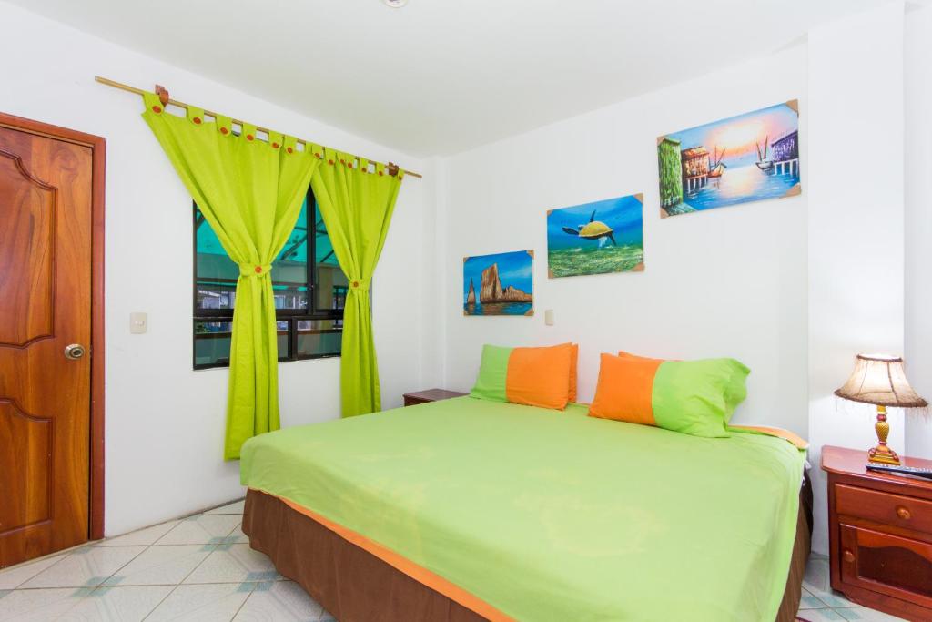 a bedroom with a green bed and a window at The Island Home in Puerto Ayora