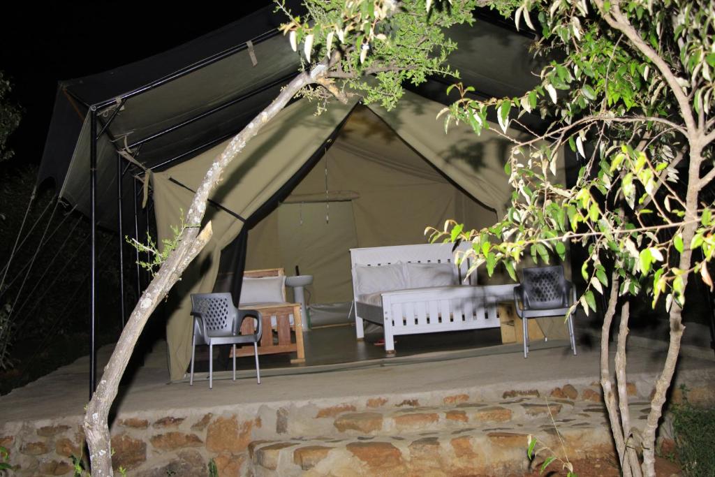 a tent with two benches and two chairs in it at Nature Lovers Camp in Sekenani