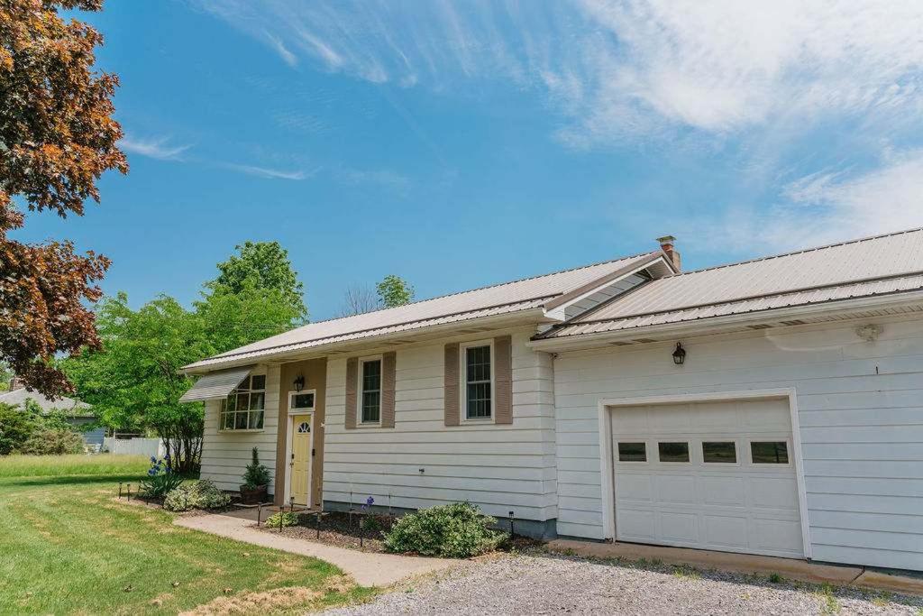 a white house with a garage at Family Friendly Getaway with Fire Pit & Swing Set in Geneva