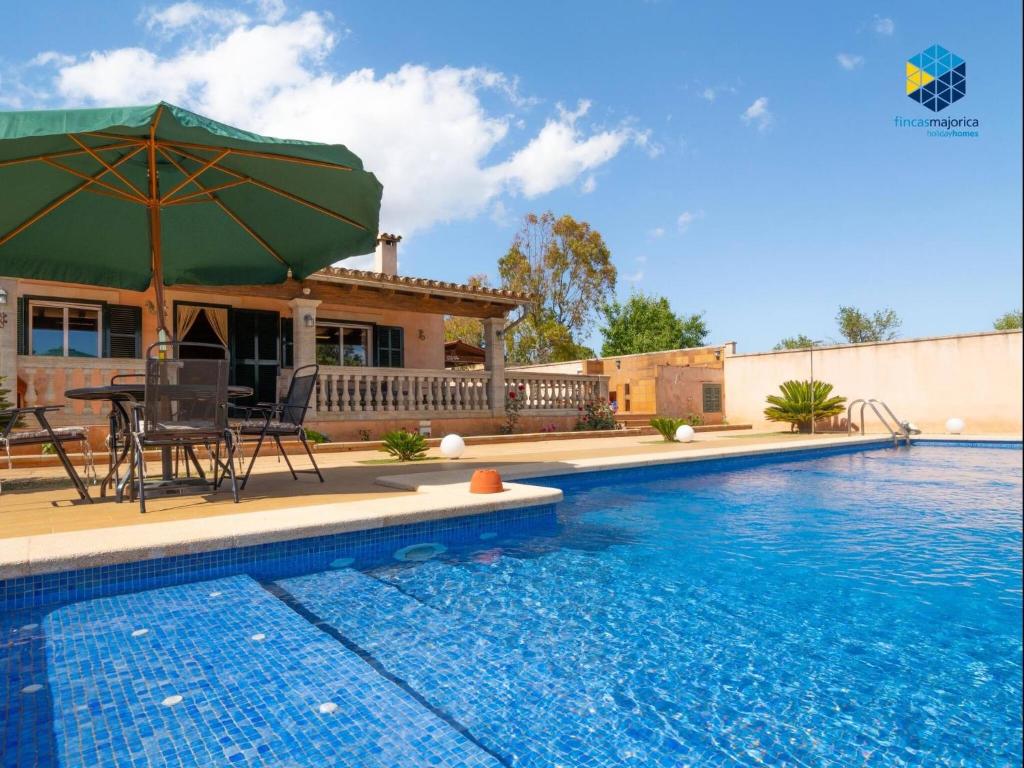 a house with a swimming pool with a table and an umbrella at Casa Bon Nadal in Llucmajor