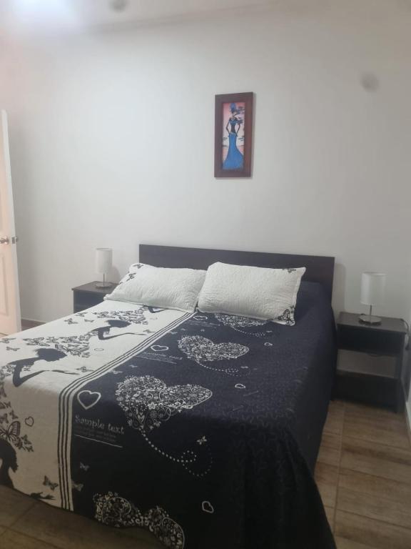 a bed with a black and white blanket on it at Hotel santa Rosa spa in Ovalle