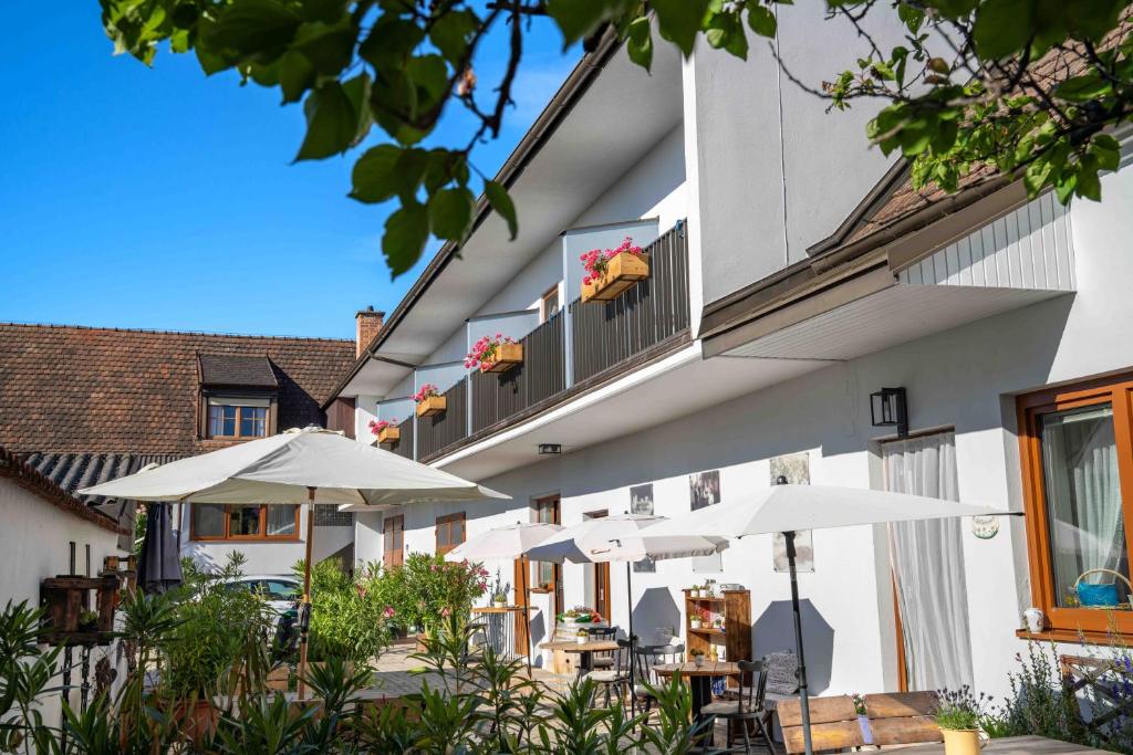 a building with tables and umbrellas in front of it at Gästehaus Elfriede in Mörbisch am See