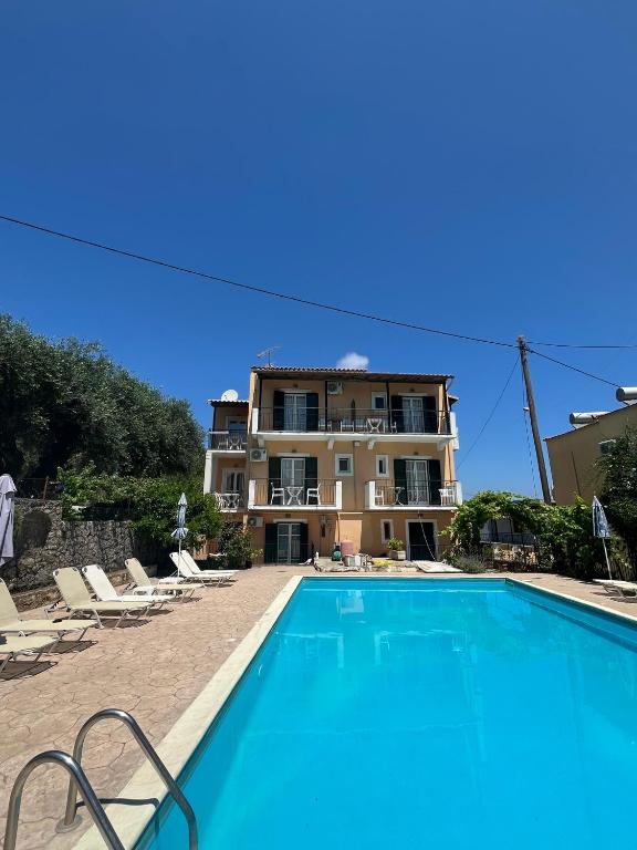 a villa with a swimming pool in front of a building at Avgoustina Venus Studios in Benitses