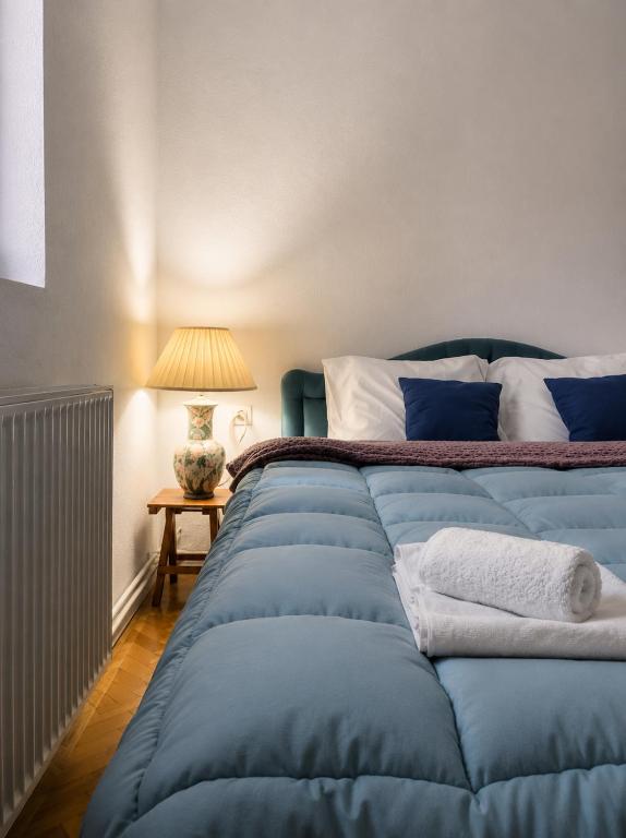 a large blue bed in a room with a lamp at Garden Oasis Apartment in Veles