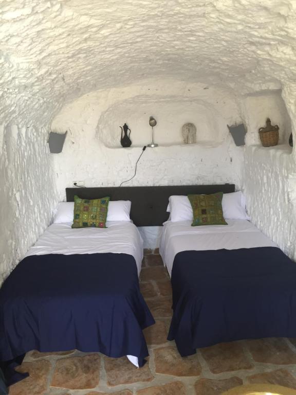 a room with two beds in a white room at The Cave of Dreams in Baza