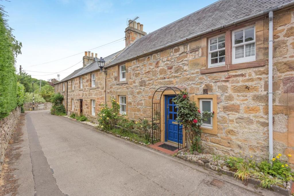 an old stone house with a blue door on a street at 3 Bed in Dornoch oc-o44869 in Dornoch
