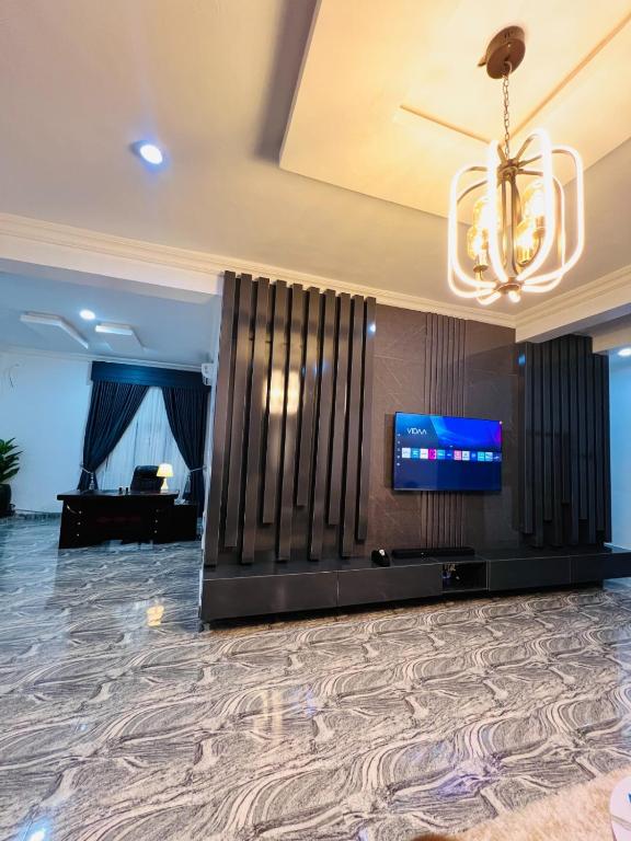 a large room with a flat screen tv and a chandelier at Kaizen Luxury Homes in Abuja