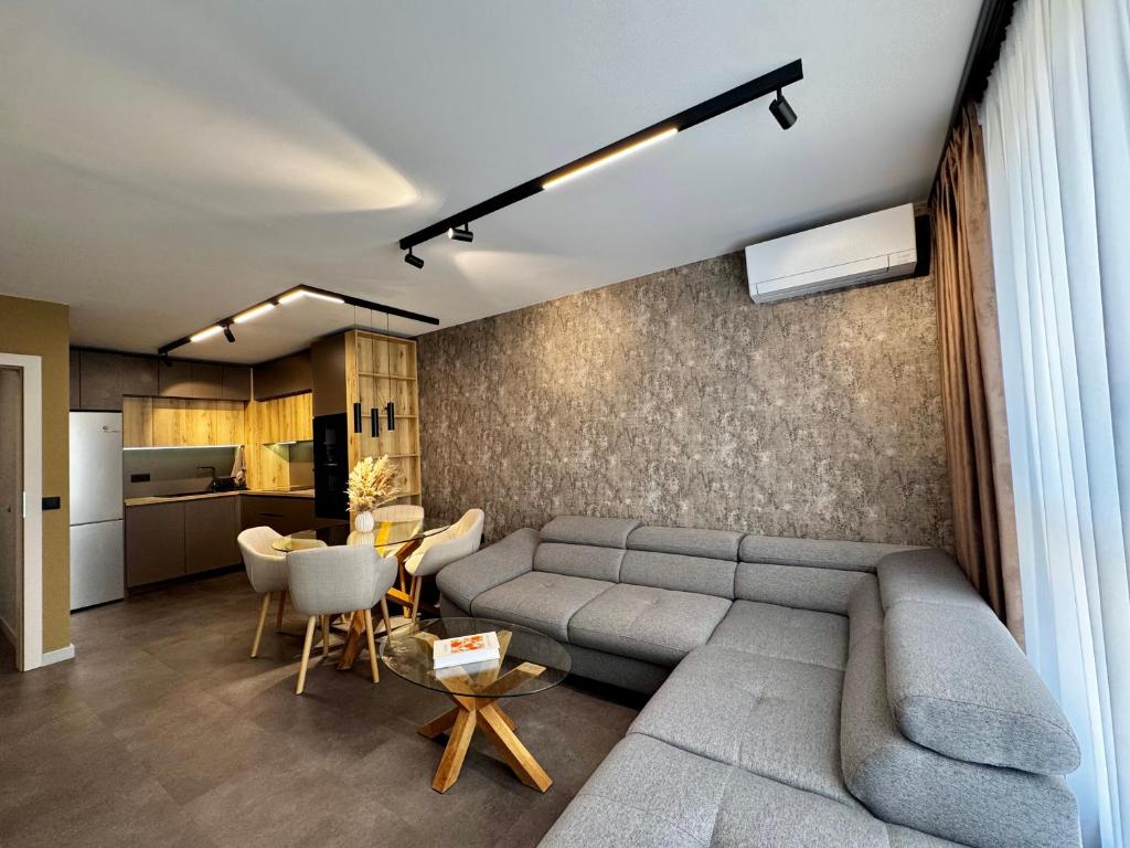 a living room with a gray couch and a kitchen at Apartment Sonata in Varna City