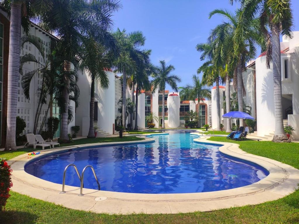 a swimming pool with palm trees and buildings at Top Pool Condo in Ixtapa's Hotel Area in Ixtapa