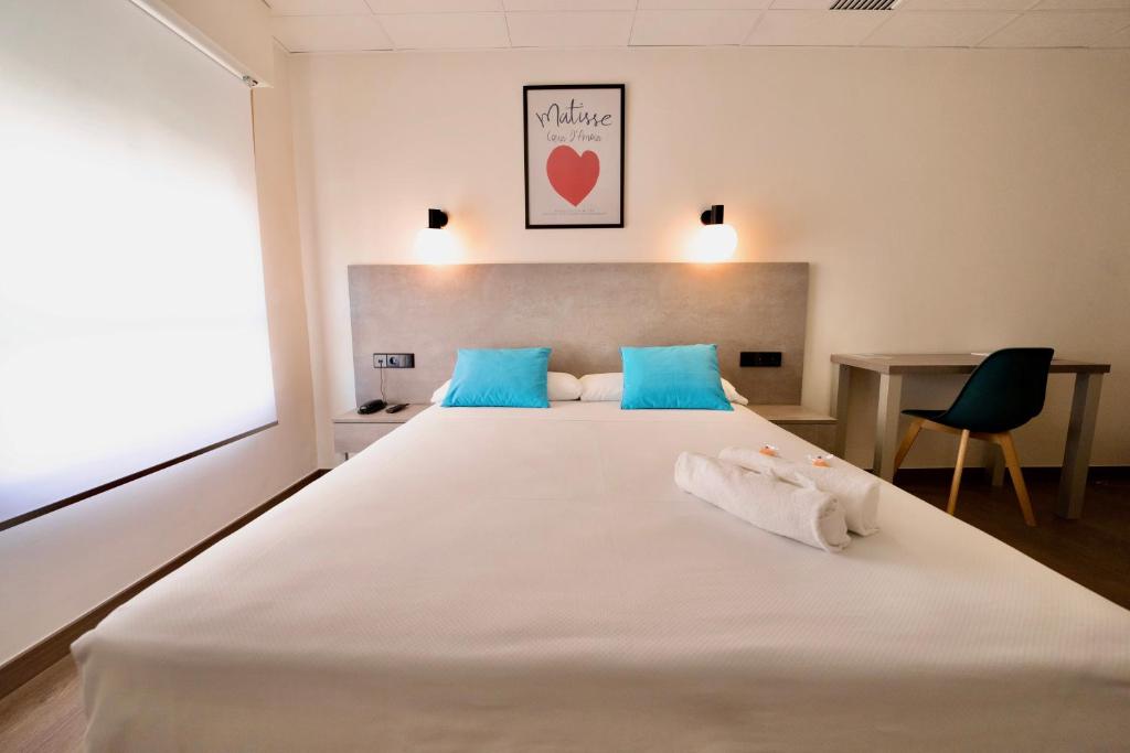 a bedroom with a large white bed with blue pillows at Hotel Universal Murcia in Murcia
