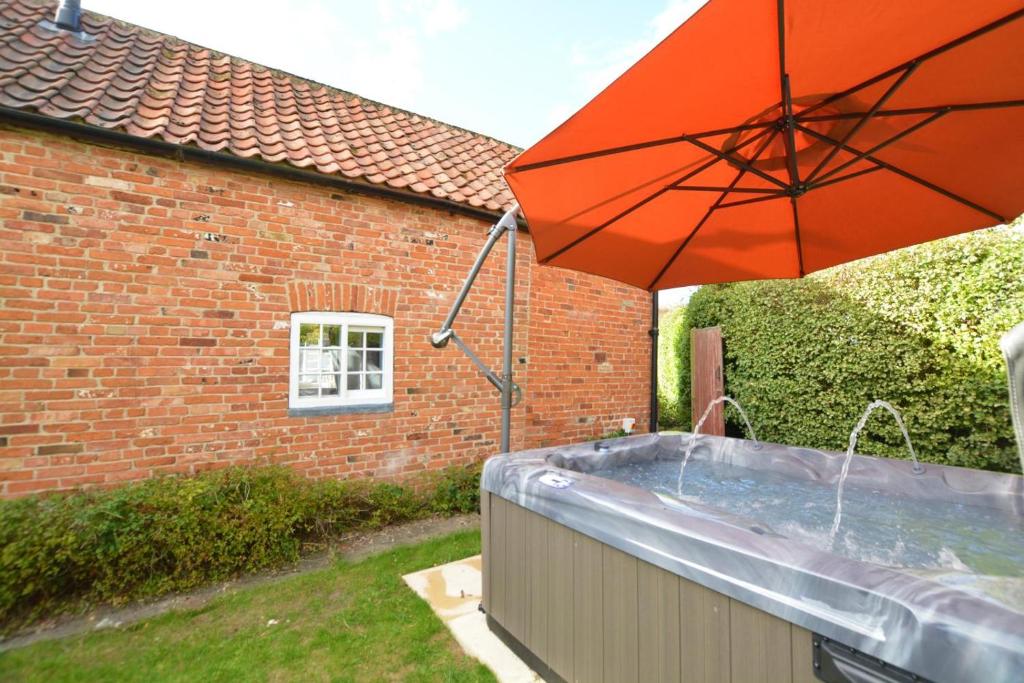 a hot tub with an umbrella in a yard at 1 Bed in Gainsborough oc-66230 in Heapham