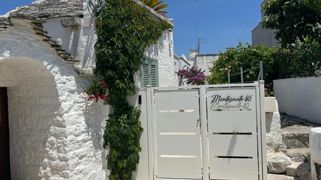 a white building with a white door with ivy on it at Montesanto 60 Suite & Relax Alberobello in Alberobello