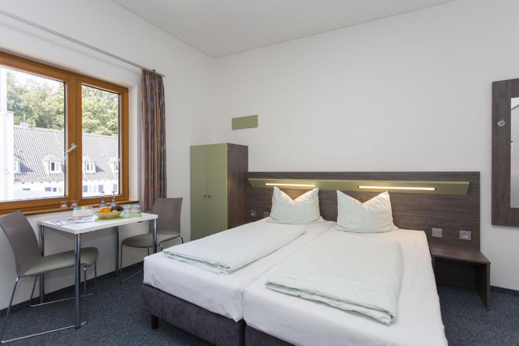 アーヘンにあるユーゲントヘアベルゲ アーヘンの大きなベッドとテーブルが備わるホテルルームです。