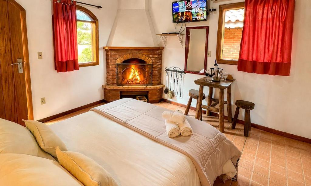 a bedroom with a bed with a fireplace in it at VELINN Pousada Locanda Belvedere in Monte Verde