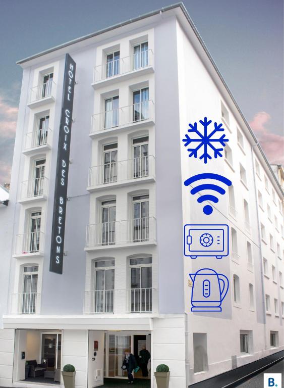 a white building with a sign on the side of it at Hôtel Croix des Bretons - Lourdes Pyrénées in Lourdes