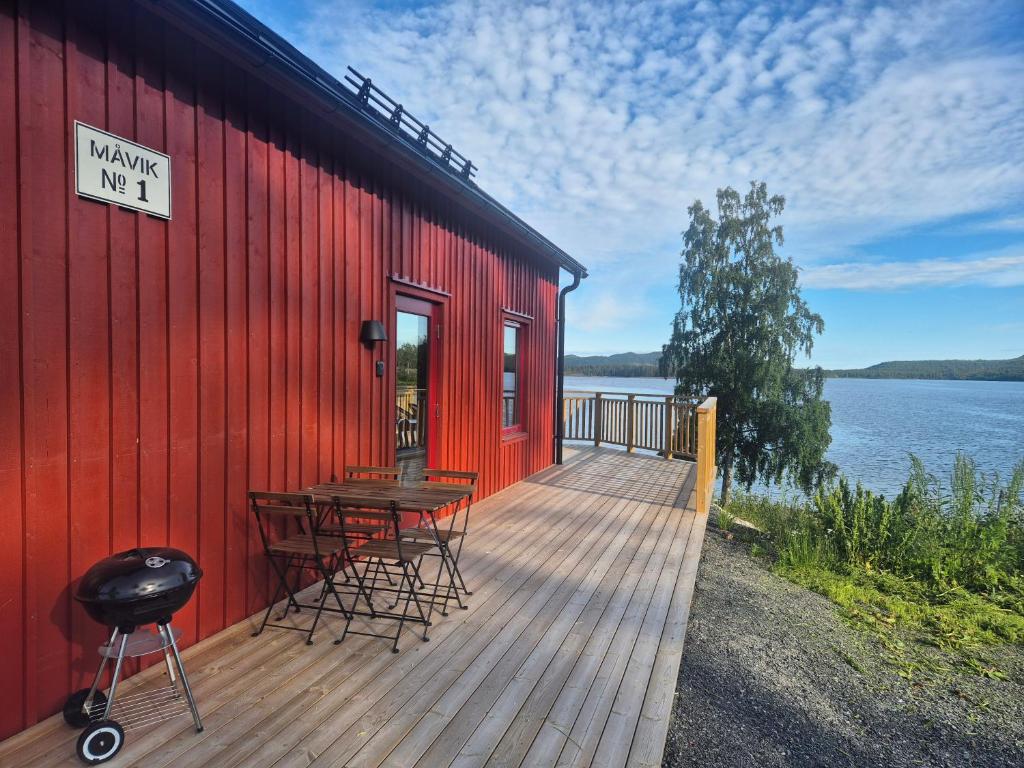 a red building with a table and chairs on a deck at Måvikens havsstugor in Måviken