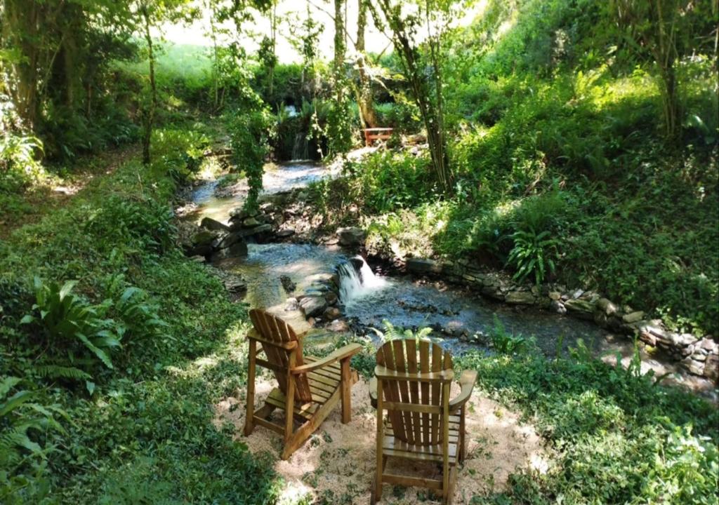 two chairs sitting next to a stream in a garden at Gîte Terra Bosca in Cambounès