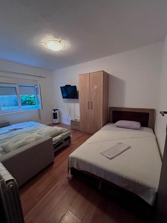 a bedroom with two beds and a tv in it at Sobe Mračević in Sutorina