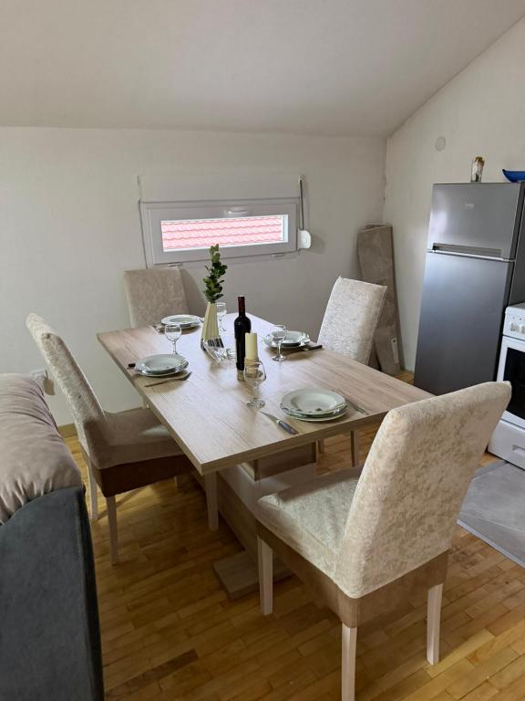 a dining room table with chairs and a refrigerator at Airport Studio apartman ravna gora in Mitrovići