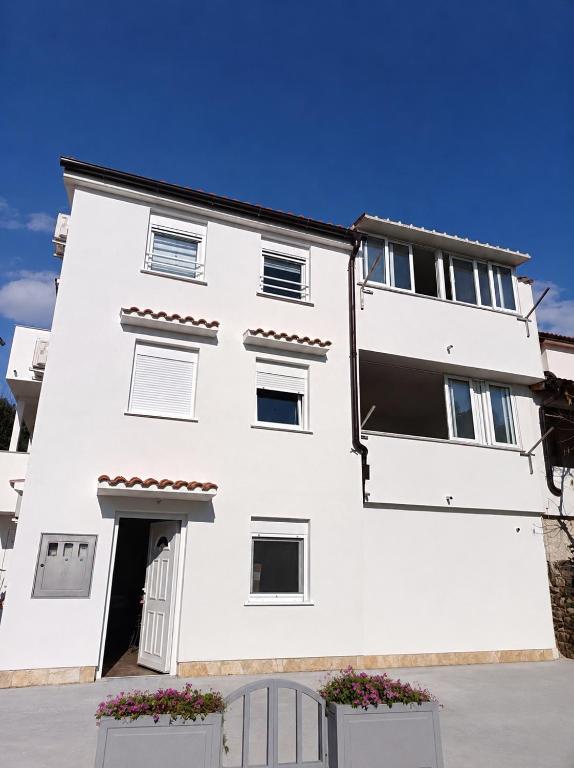 a white building with a gate in front of it at Jakišnica Apartment in Lun