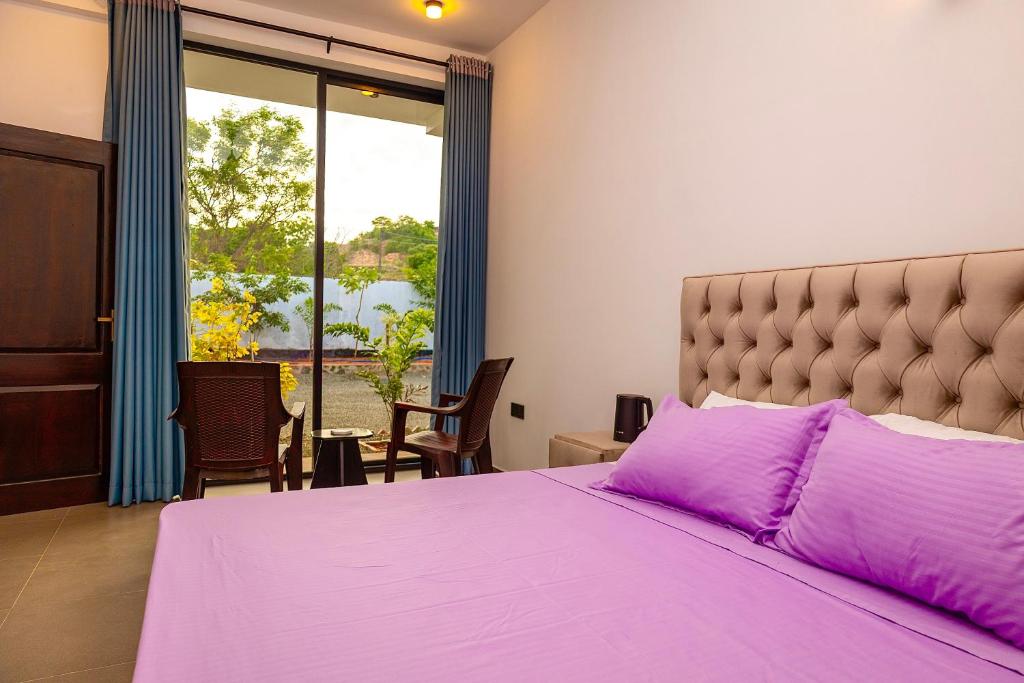 a bedroom with a large purple bed with a large window at Port Royal Residence in Trincomalee