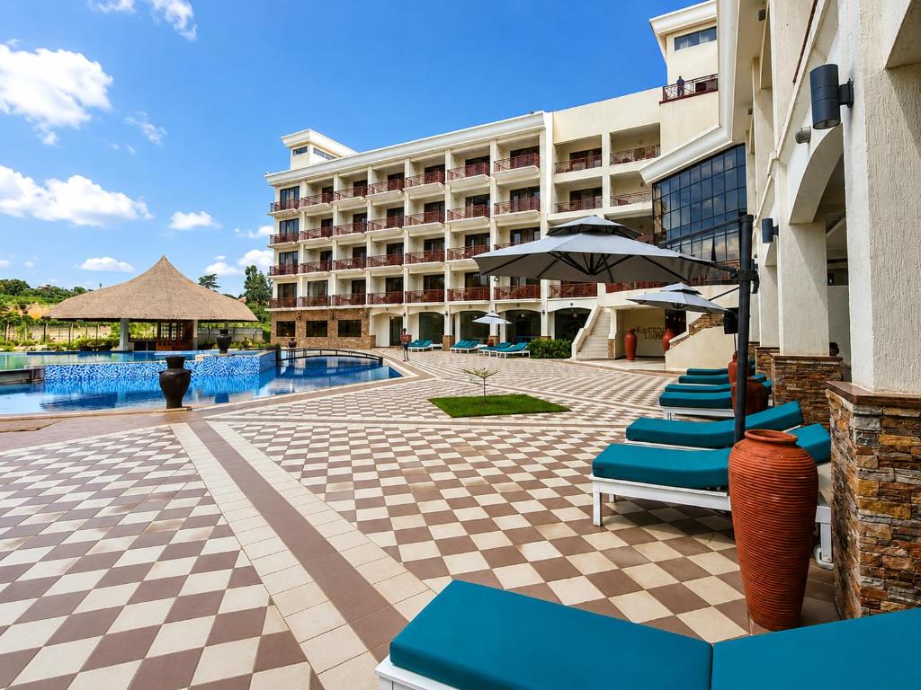 a hotel with a pool and chairs and an umbrella at Kampala Nile Resort in Seeta