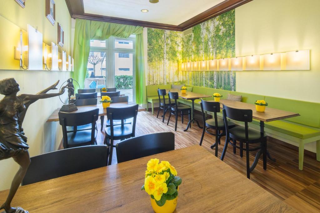 a restaurant with green walls and tables and chairs at Hotel Ambassador in Solothurn