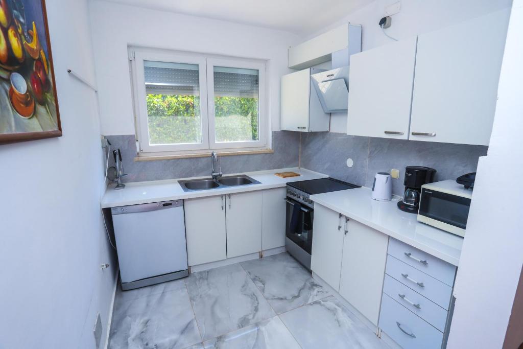 a kitchen with white cabinets and a sink and a window at Medo in Novigrad Istria