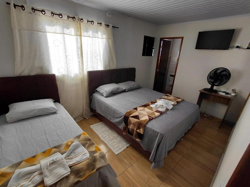 a bedroom with two beds and a table and a window at Kurten Hotelaria in Cândido de Abreu