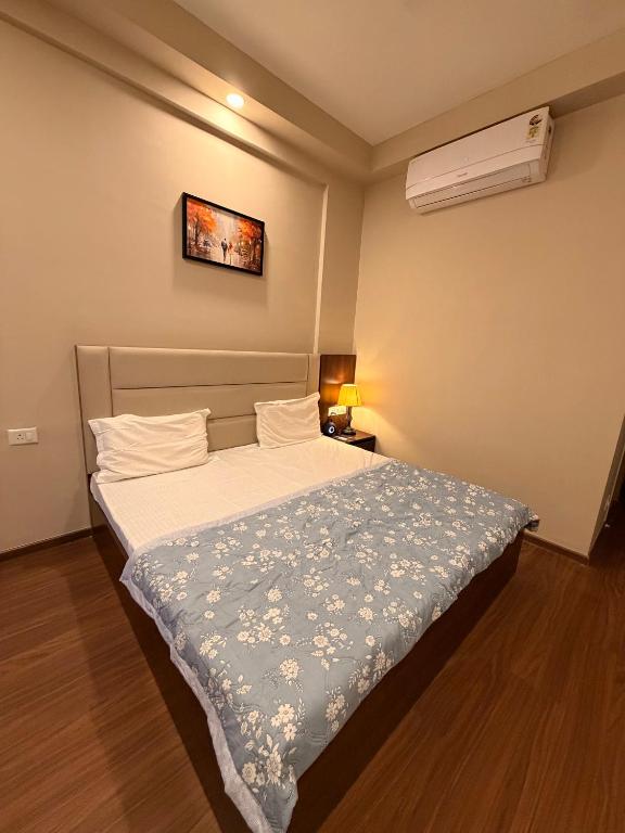 a bedroom with a bed with a blue and white blanket at Av stays in Greater Noida