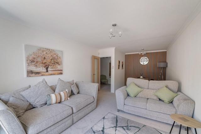 a living room with two couches and a table at Fairways - Flat 3 in Weston-super-Mare