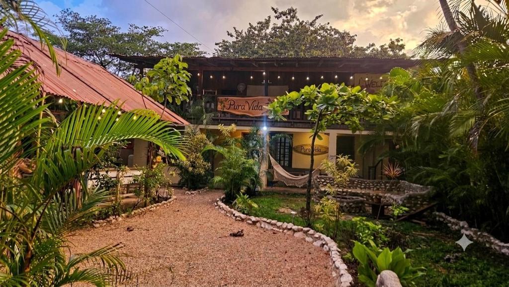 a garden in front of a house with a bench at Woodstock Hostel in Sámara